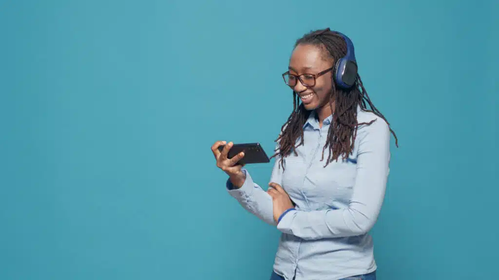 adulto joven viendo una película aplicación para teléfono inteligente usando auriculares inalámbricos escuchar programa de televisión película en línea red de internet disfrutando de un canal de televisión de comedia divertida usando un teléfono móvil