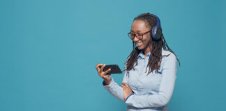young adult watching movie smartphone app using wireless headphones listen tv show film online internet network enjoying funny comedy television channel using mobile phone