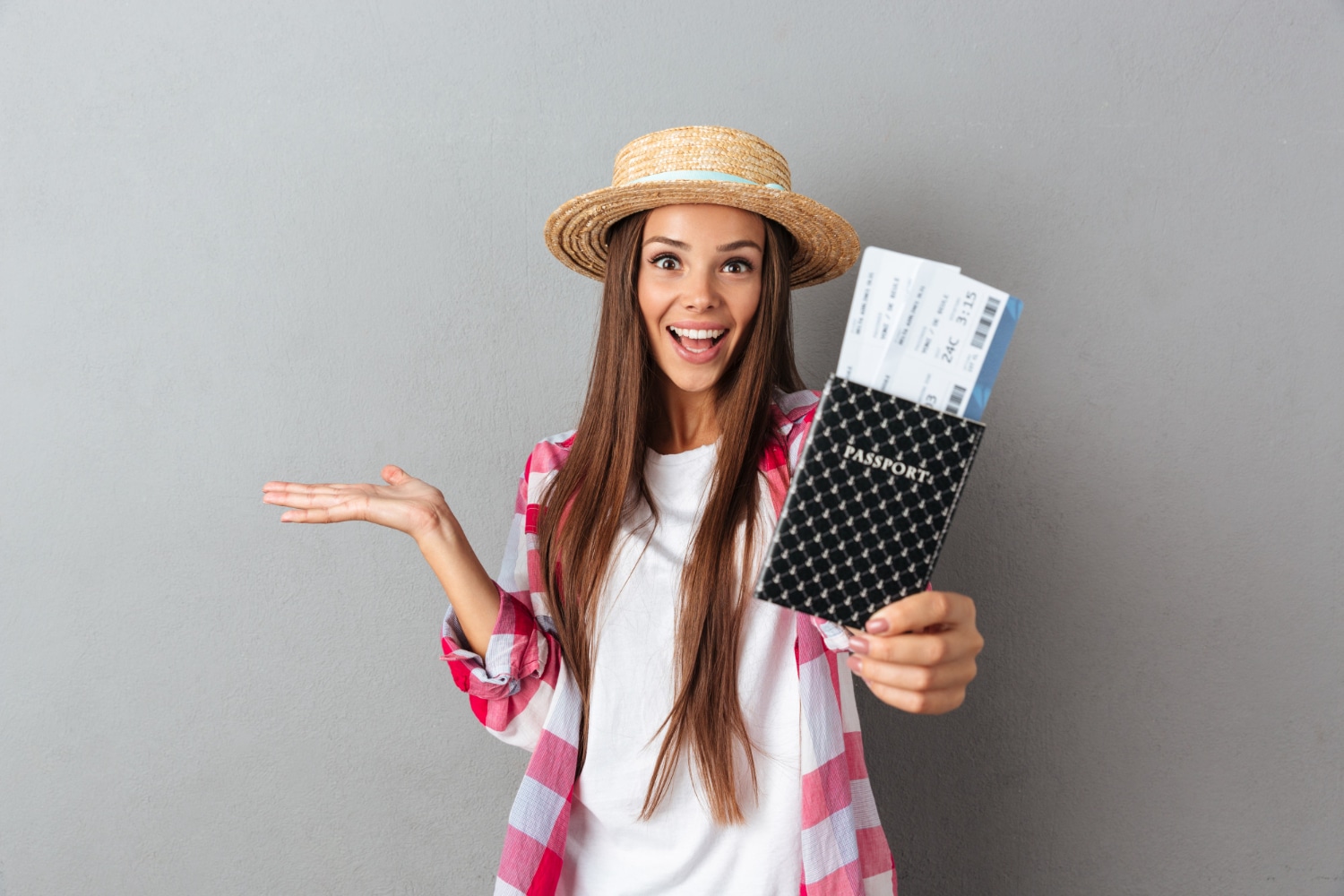 मुस्कुराती हुई प्रसन्न महिला यात्री स्ट्रॉ टोपी का क्लोज़अप चित्र, जिसमें हवाई जहाज के टिकट के साथ पासपोर्ट दिखाया गया है