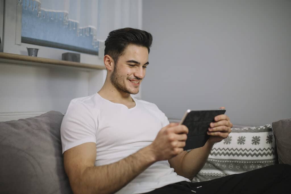smiling man using tablet couch