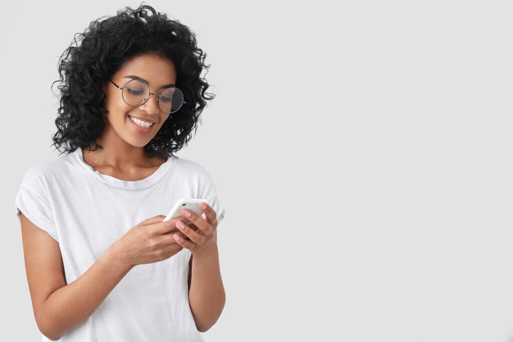 cheerful african american with crisp hair holds modern smart phone happy smile
