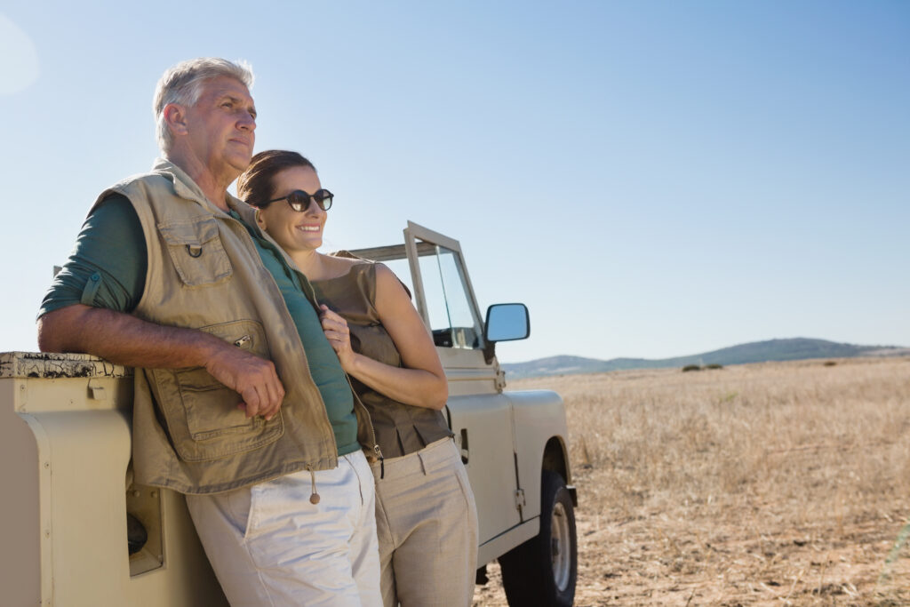 couple looking away while standing by vehicle field