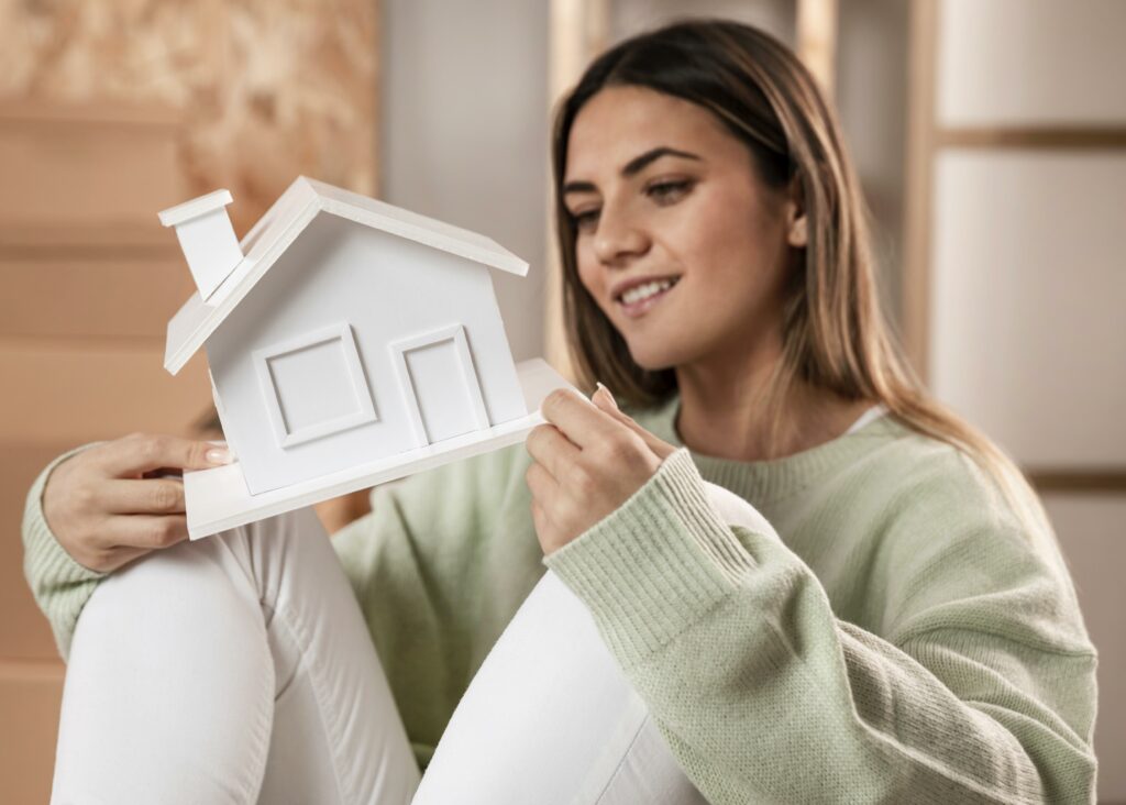 mujer de tiro medio sosteniendo una casa pequeña