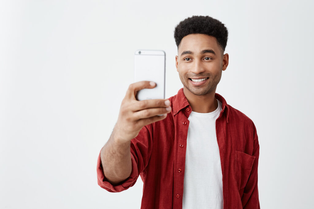 portrait young handsome tan skinned american male with afro hairstyle casual fashionable outfit smiling with teeth taking photo friends during vacation