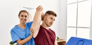 young hispanic physioterapist woman make arm rehab treatment man clinic 1